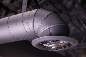 Close-up of a metallic air duct and vent in an industrial setting.